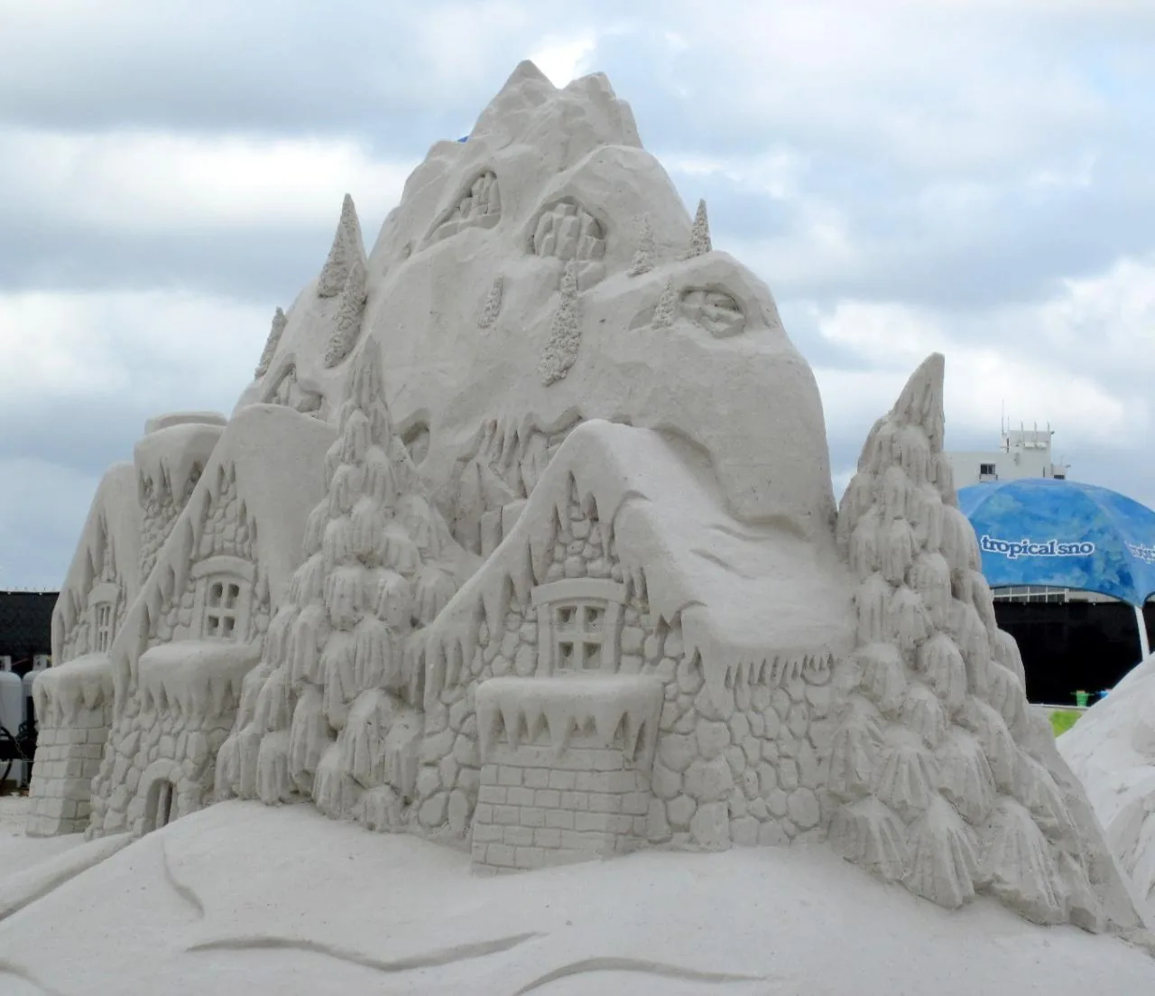 A sand sculpture of snow-covered cottages, pine trees and a mountain at the sand sculpting competition on Fort Myers Beach.